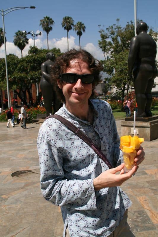 Simon eating mango in Plaza Botero, Medellin