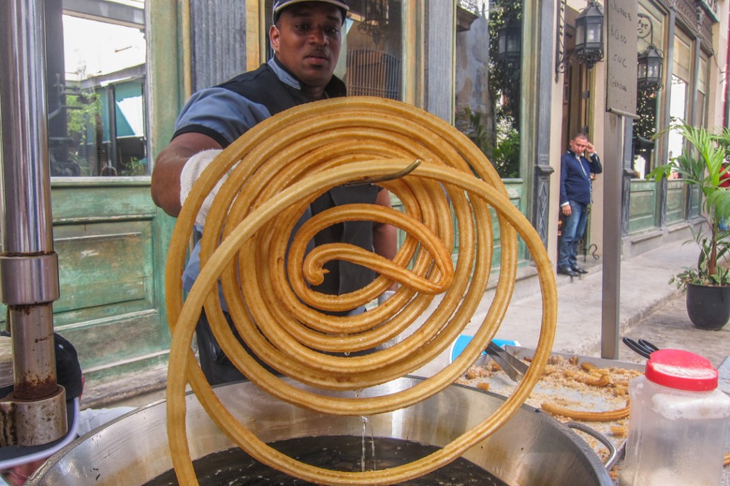 A Churro seller holds up a huge spiral of deep fried churros