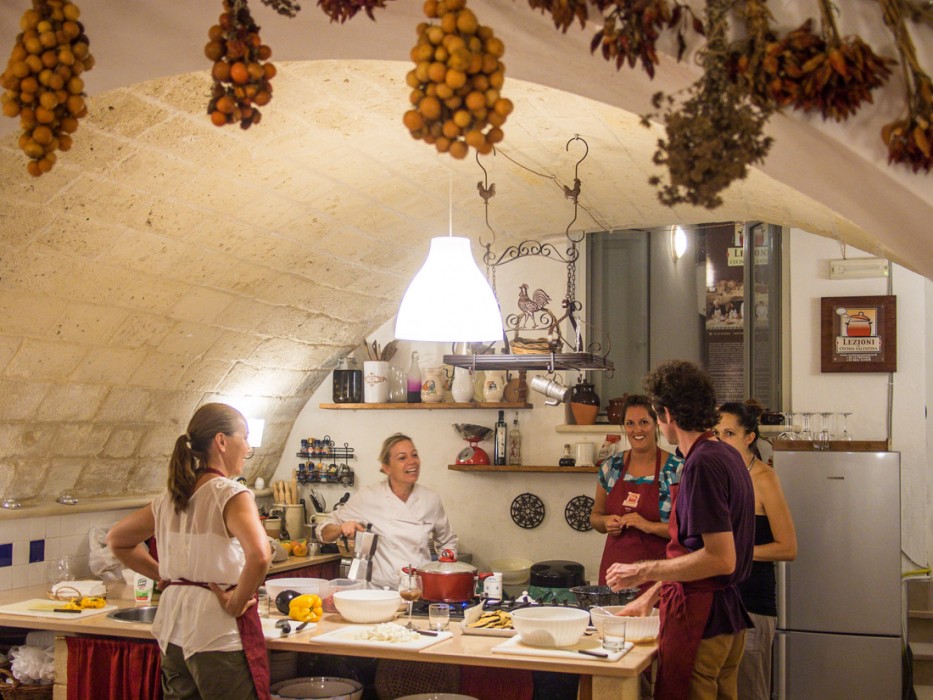 Cooking class in a room with stone arched ceiling decorated with hanging dried tomatoes and herbs, Lecce, Italy