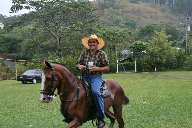 Costa Rican cowboy drinking on horse back