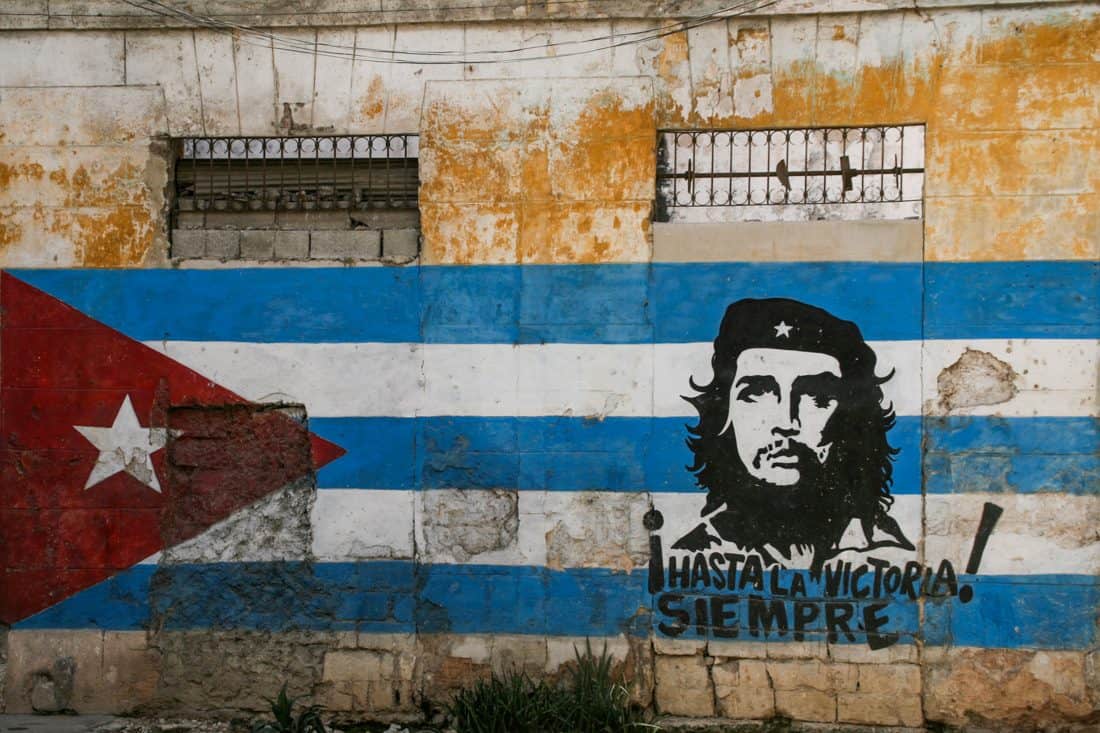 A faded orange building has the cuban flag painted along its entire length, with Che Guevara's face covering the right hand side