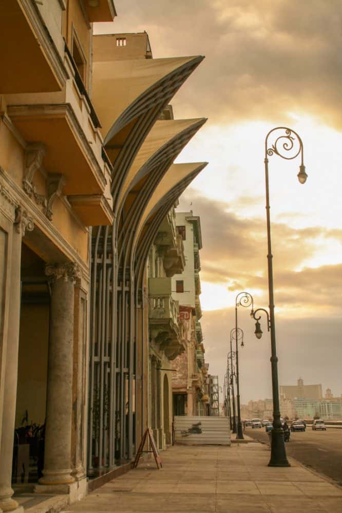 The glow of the sunset warms the whites and pale oranges of these Malecón buildings