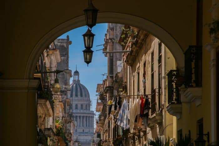 An arch frames a house with its washing hung out as the Cuban capital building stands in the background