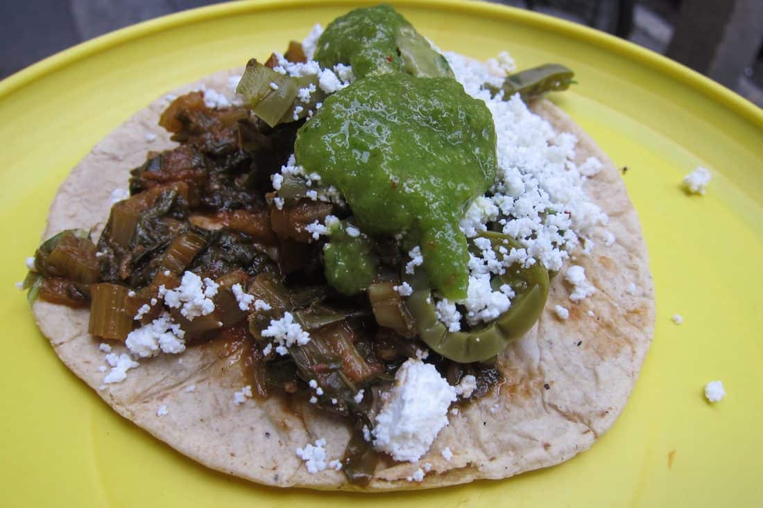 Chard taco topped with cactus, cheese, and green salsa