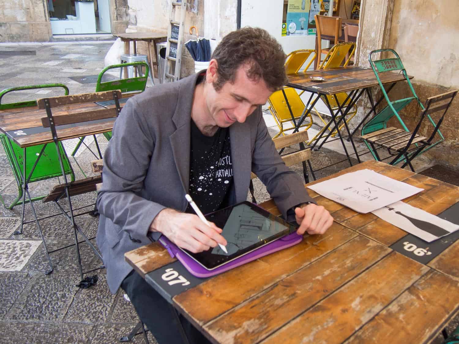 The Gramercy mens travel blazer with a black tshirt and jeans in a cafe in Lecce