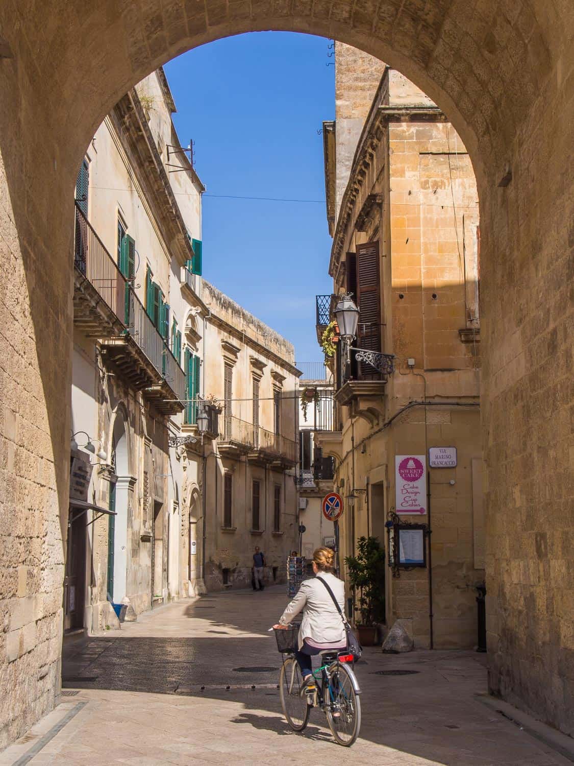 Woman cycling up a backstreet in Lecce, Puglia, Italy