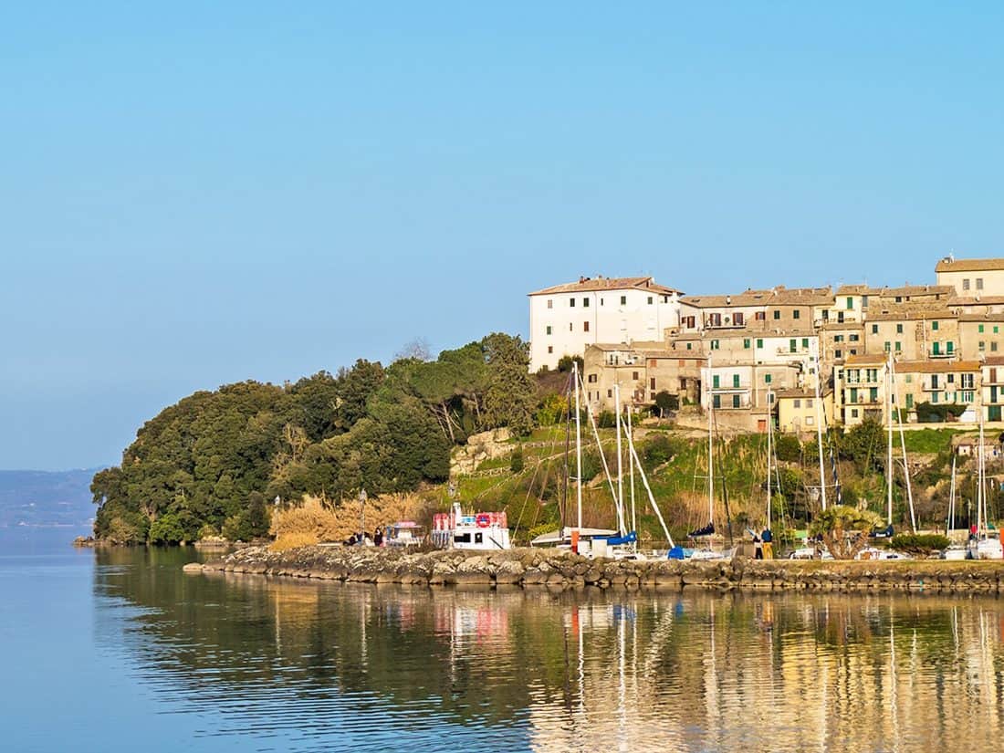 Reflections of boats and buildings in Bolsena Lake near Rome in Italy