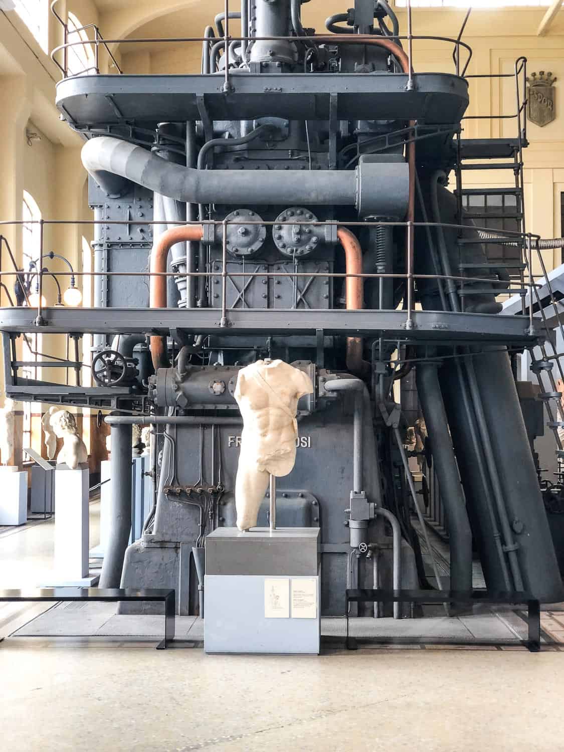 Sculpture in front of a giant diesel engine in Centrale Montemartini museum in Ostiense, Rome, Italy