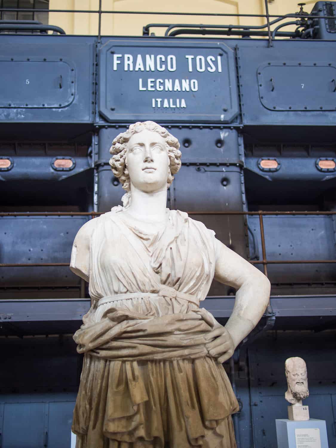 Sculpture in front of an industrial machine in Centrale Montemartini museum in Ostiense, Rome, Italy