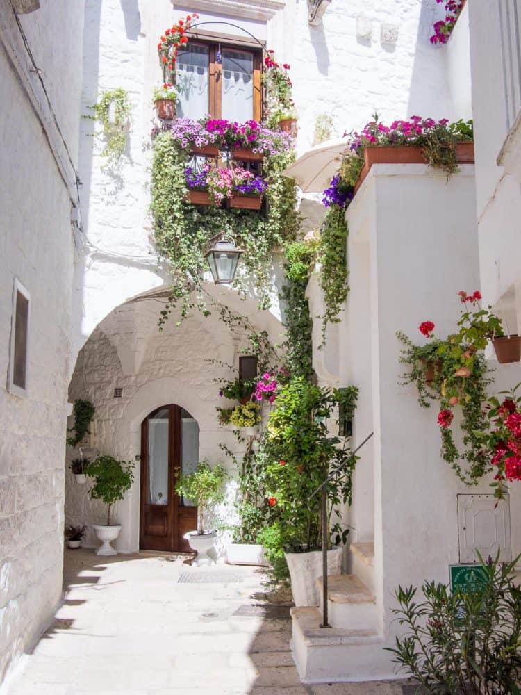 Narrow white street decorated with flowers in Cisternino, Puglia
