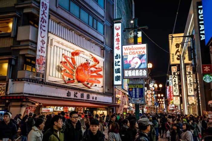 Busy streets and giant crab of Dotonburi in Osaka at night, a popular day trip from Kyoto