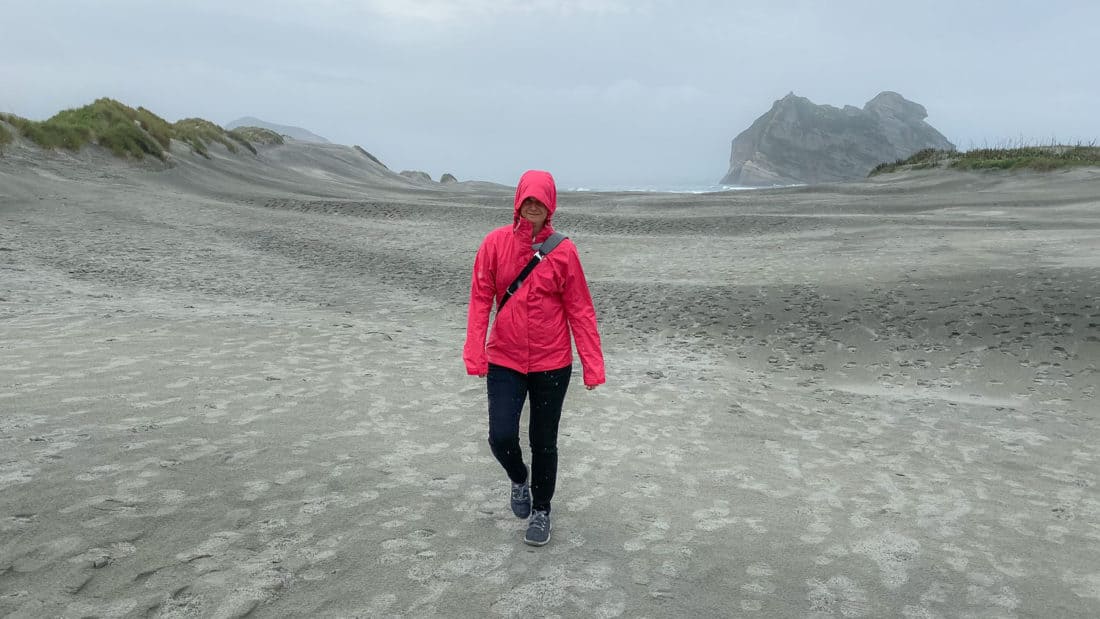 Erin wearing Allbirds wool runners on a chilly, drizzly walk on Wharariki Beach in New Zealand