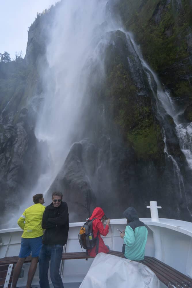 Simon standing under a waterfall on a Milford Sound cruise