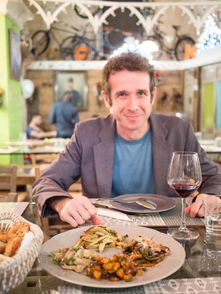 Simon with glass of red wine and vegetarian antipasto in a restaurant in Lecce, Italy