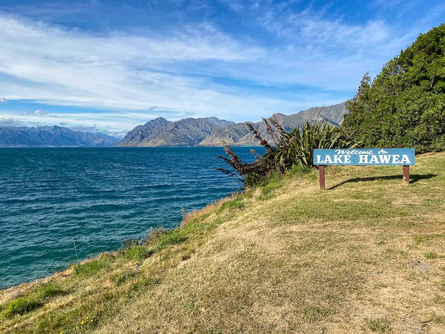 Lakeside view of Lake Hawea with mountains and sign, Wanaka, New Zealand