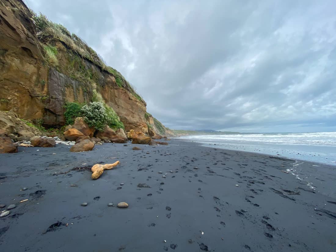 The black sand and orange cliffs of Back Beach in New Plymouth, New Zealand