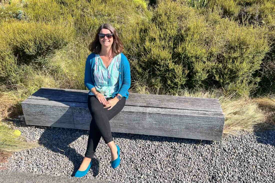 Erin sitting on a bench wearing Emerald Allbirds Tree Breezers