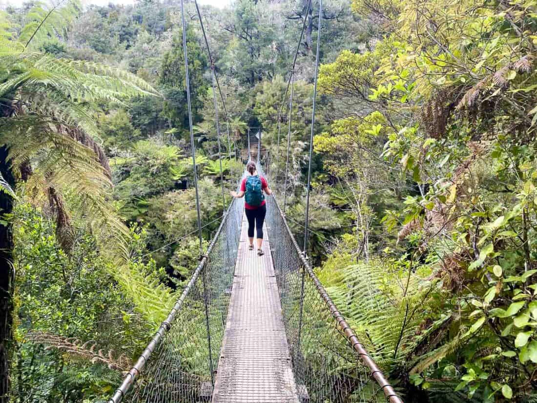 Hiker crossing the Falls River swing bridge on the Abel Tasman coastal track