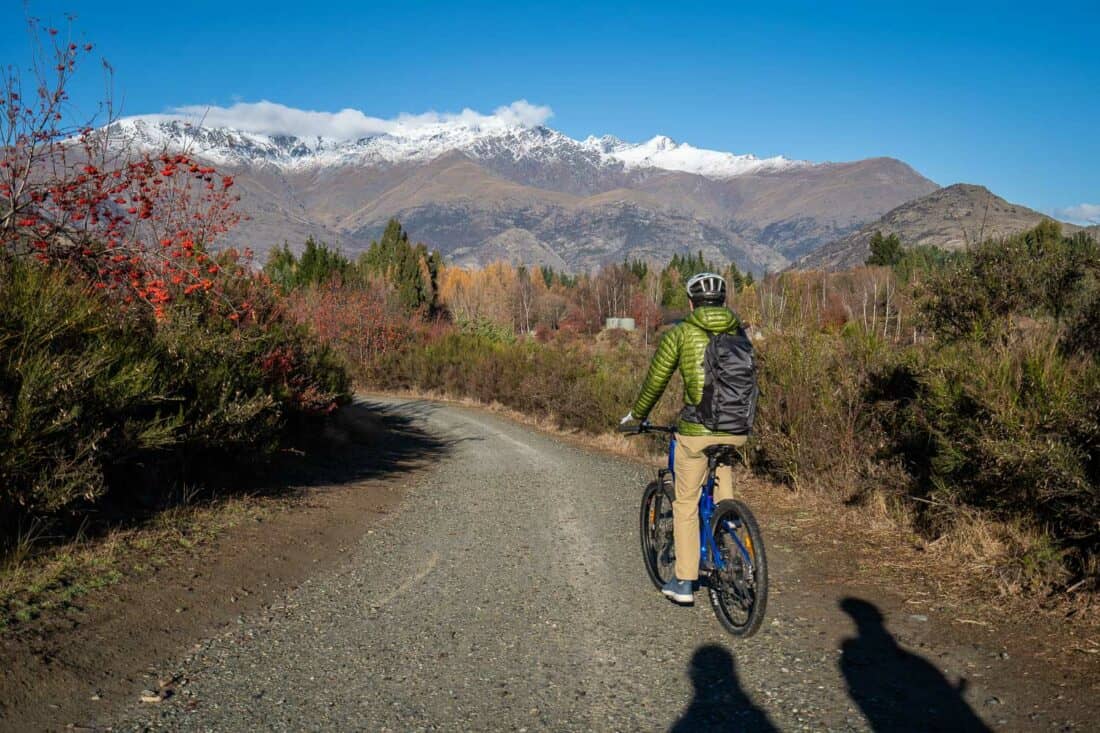 Cycling towards snowy mountains on the Arrowtown to Gibbston Valley bike trail