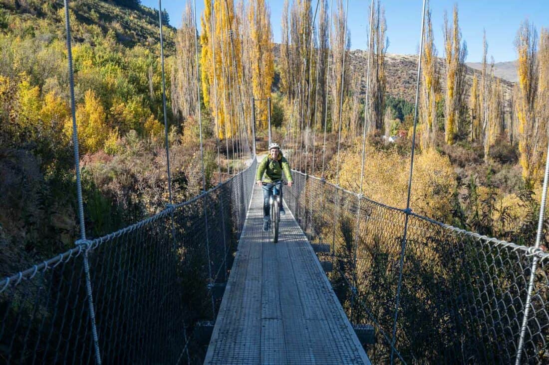 Cycling over the Southern Discoveries suspension bridge in autumn on the Arrow River Bridges Trail