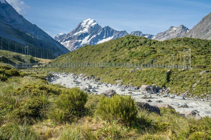 Hikers on a suspension bridge on the Hooker Valley Track at Aoraki Mt Cook, one of the best things to do in the South Island New Zealand