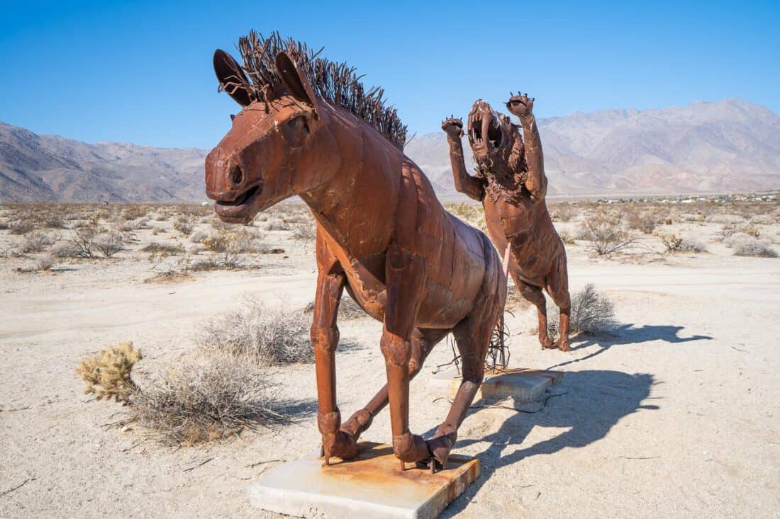 Metal sculpture of sabertooth cat chasing a horse in Galleta Meadows, Borrego Springs