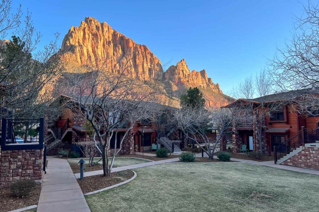 Cable Mountain Lodge with neat lawns, frosted trees and red sandstone cliff in the backdrop, Zion National Park, Utah, USA