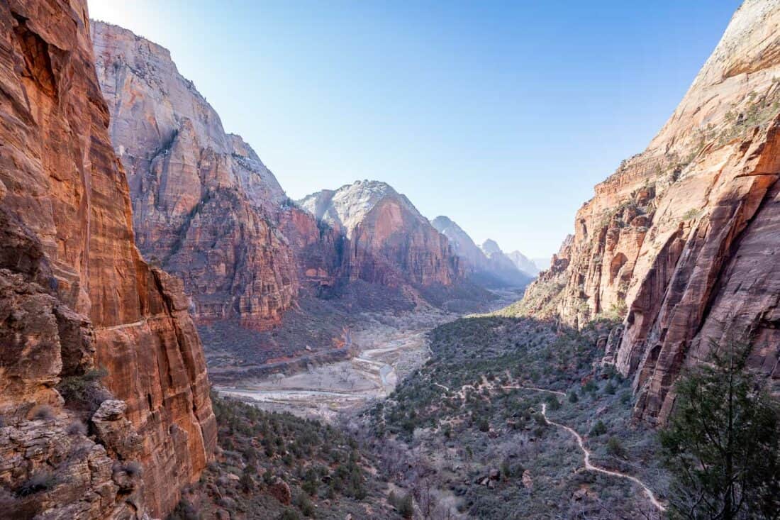 Quiet West Rim trail in Zion National Park surrounded by cliffs and a blue sky.