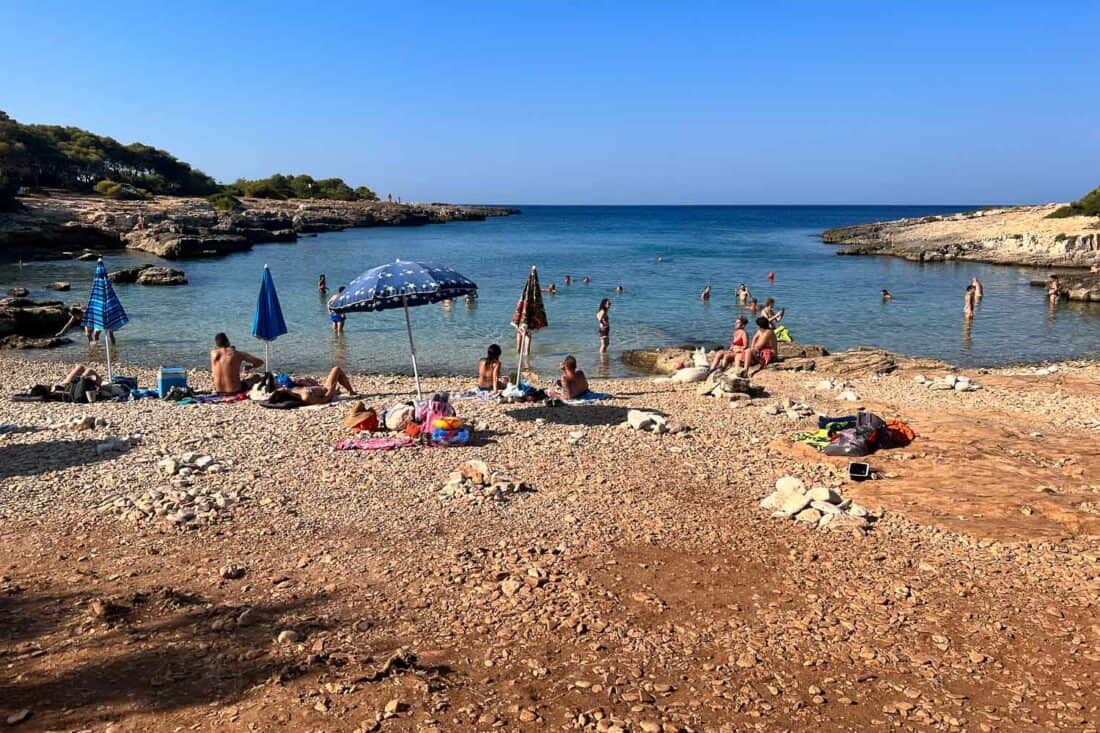 People sunbathing and swimming on Porto Selvaggio beach, Italy