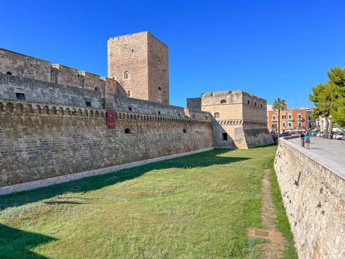 Green grassy moat surrounding Bari Castle with a bright blue sky above