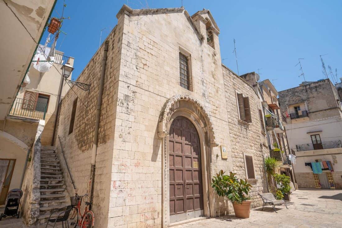 Small church in Bari Vecchia next to residential buildings and potted plants, Puglia, Italy