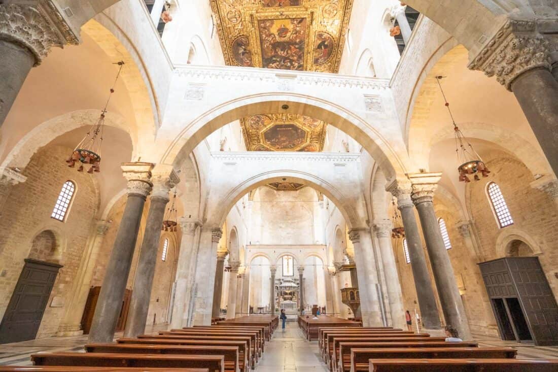 Basilica di San Nicola interior crossed with arches and gold frescoed ceiling above wooden pews