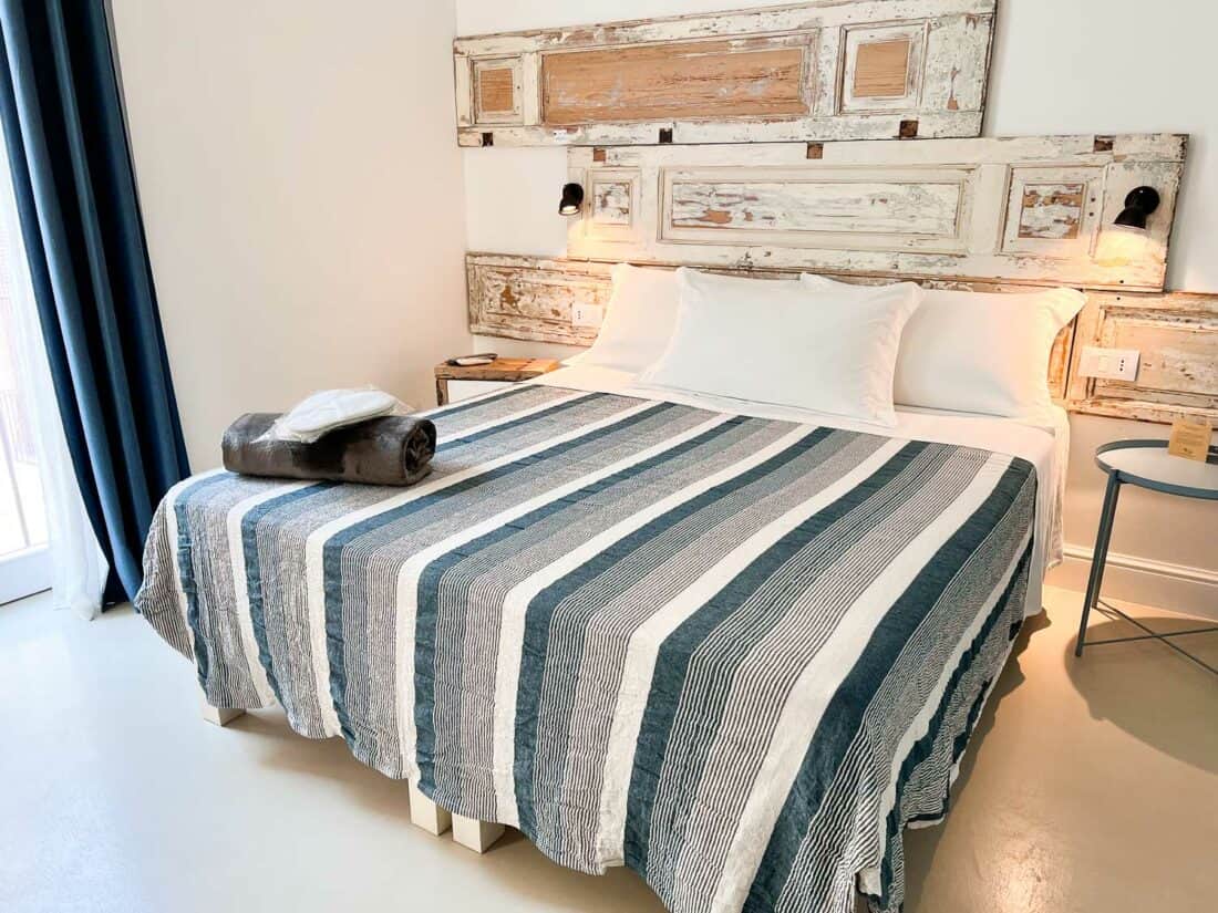 Clean modern double bedroom in B&B Murex, Bari with stripey bedding and reclaimed wood panelling decor