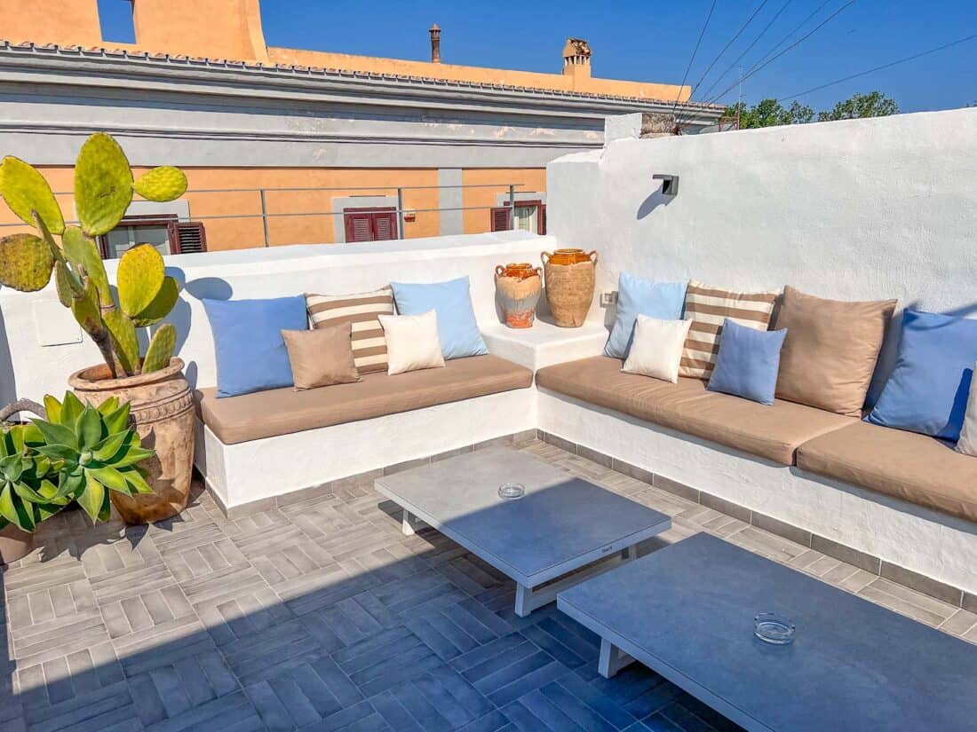 Sunny seating area on B&B Murex's rooftop bar, with cushions, low tables and large cacti in Bari, Italy