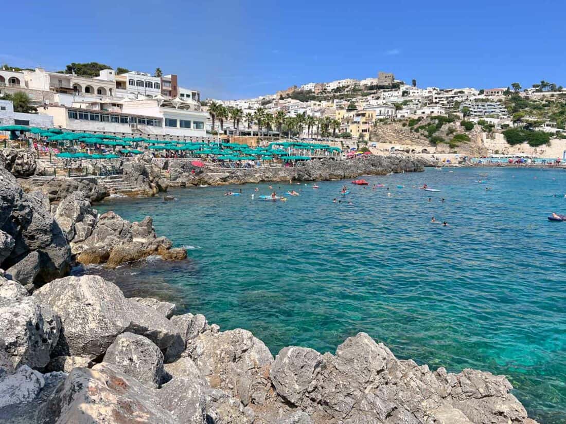 People swimming in aquamarine waters in Castro surrounded by a rocky harbour overlooked by a lido