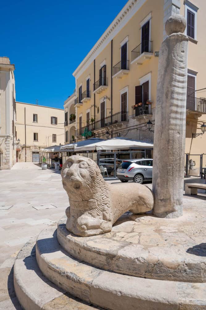 Column of Justice with old worn rope marks and worn statue in Piazza Mercantile, Bari with a blue sky in the backdrop
