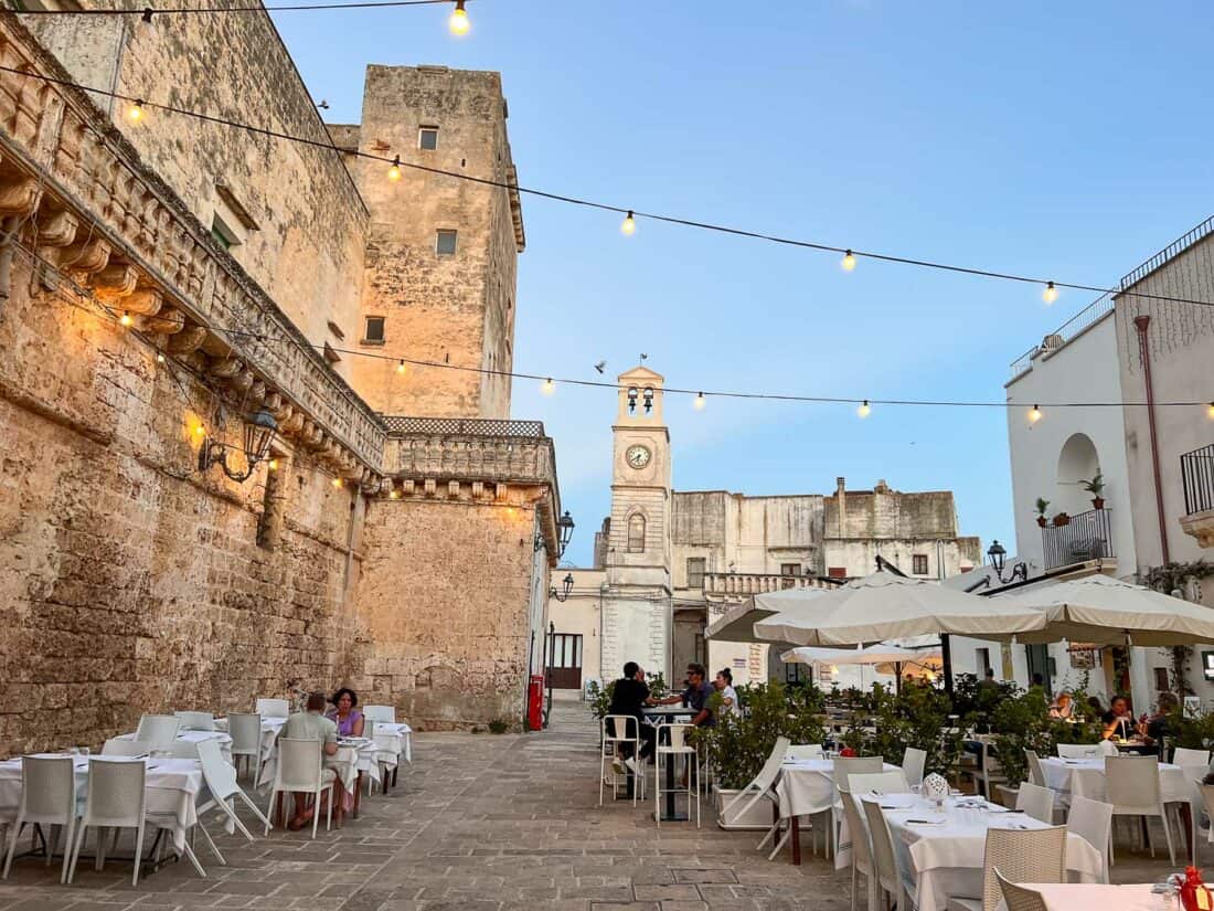People dining in a pretty quiet piazza decorated with fairy lights in Felline, Salento