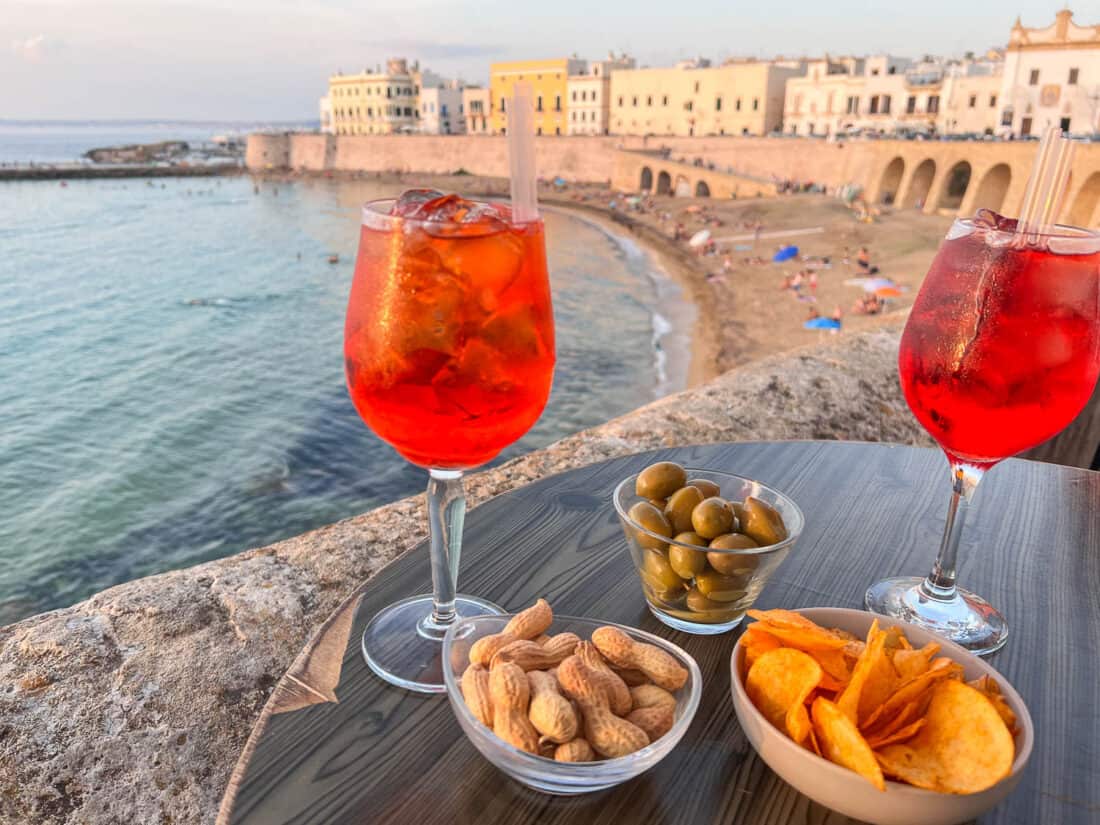 Spritzers with a variety of nibbles on a table overlooking Gallipoli beach, Salento