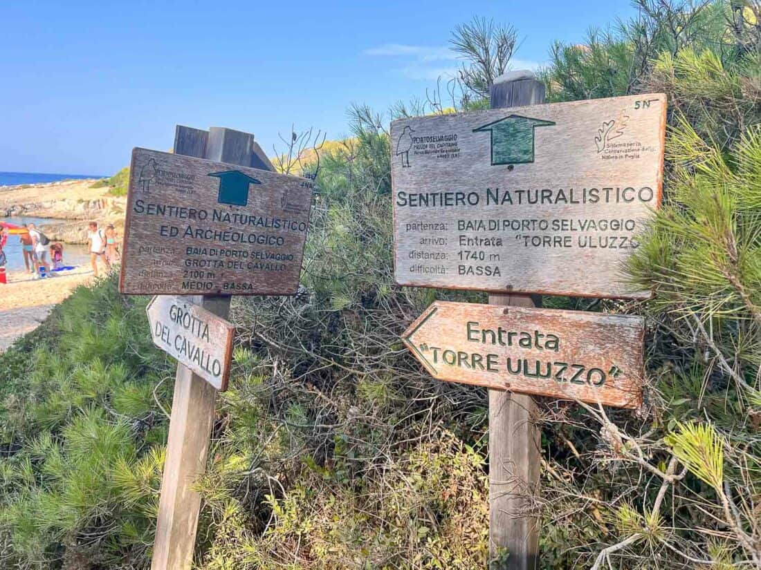 Wooden hiking trail signs at Porto Selvaggio beach, Italy