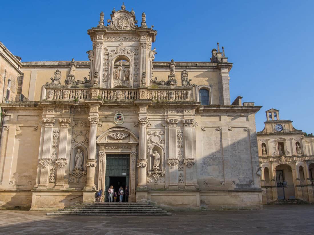 Ornate white stoned facade of Lecce Cathedral against a blue sky, Salento, Puglia, Italy
