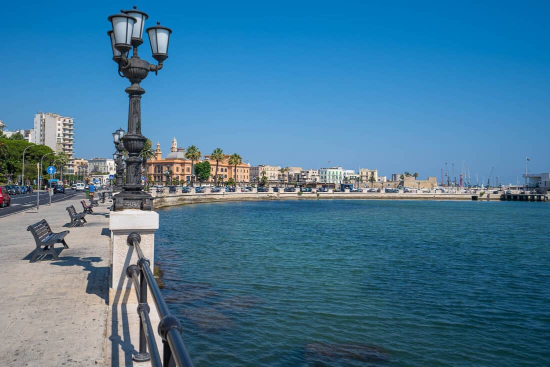 Bari's curved long Lungomare with benches and old lampposts overlooking the clear blue sea, Puglia, Italy
