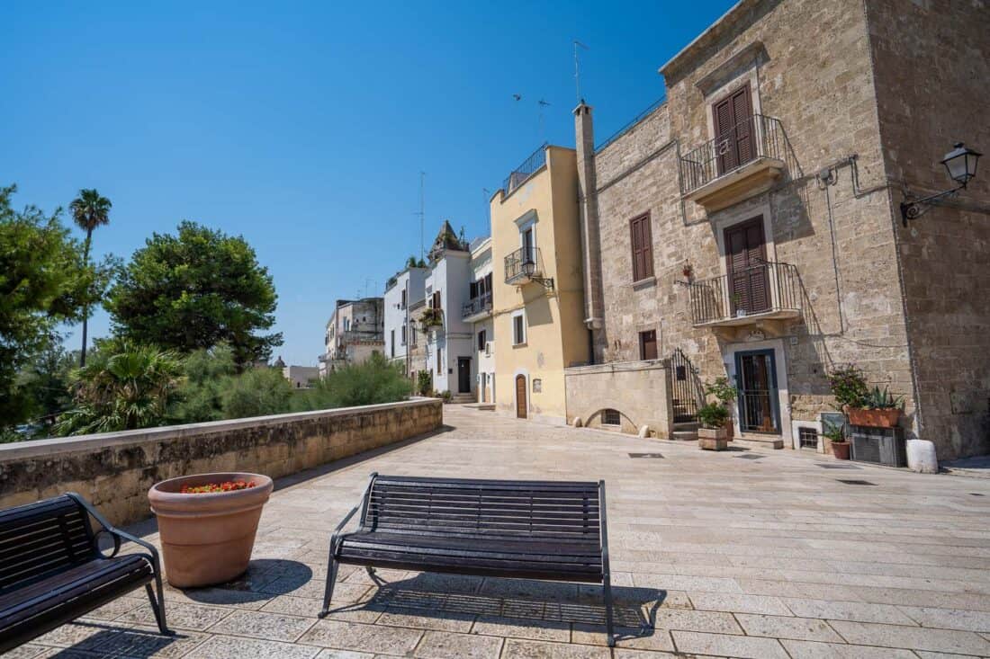 Benches and a large plant pot on the Old Walls of Bari in Italy with houses overlooking trees