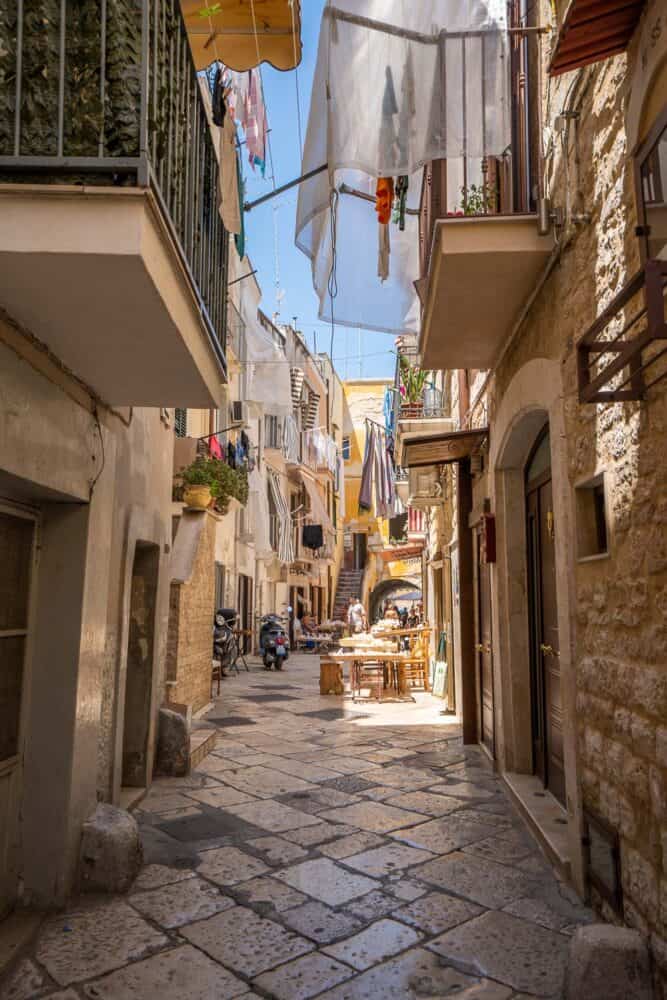 Narrow street with local women making and selling fresh pasta from tables outside their homes in Bari, Italy