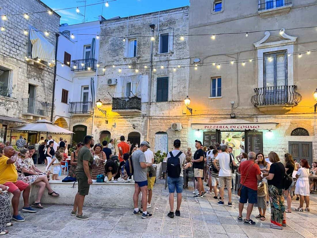 People outside Pizzeria di Cosimo in Bari on a pretty square with hanging fairy lights