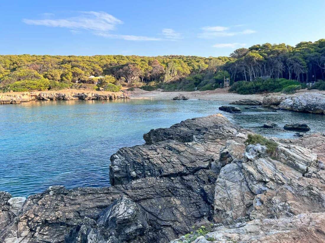 Rocky Porto Selvaggio bay with blue water backed by woods