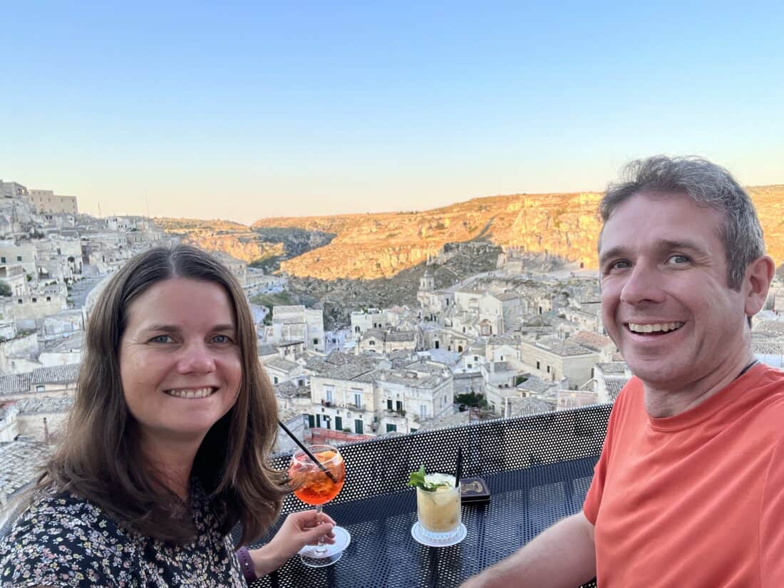 Erin and Simon with a couple of cocktails overlooking the city of Matera at sunset