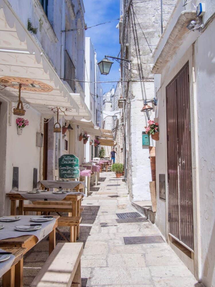 Tables of a restaurant on a narrow street in Cisternino, Puglia, Italy