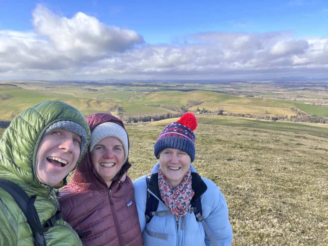 Simon, Erin, and Simon's step-mum taking a selfie in front of a wide expanse of Scottish countryside