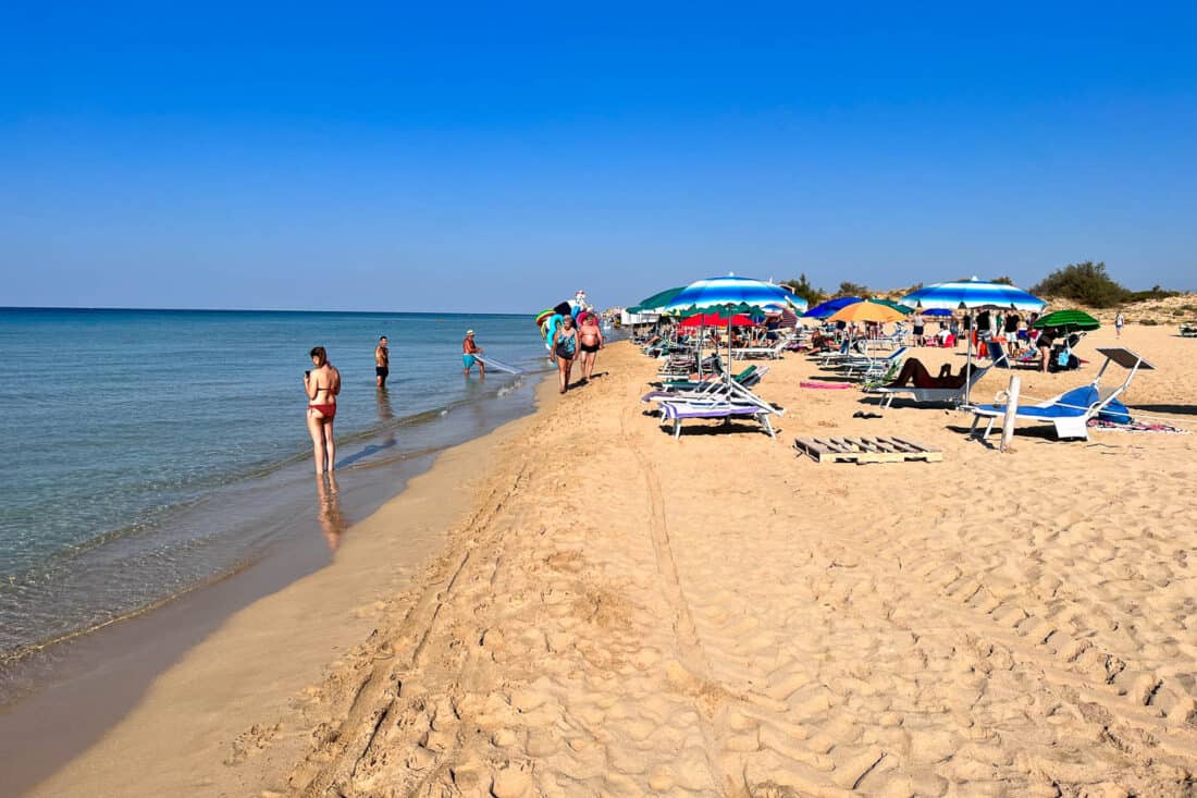 People enjoying the blue sky morning at Marina di Pescoluse beach in Puglia, Italy.