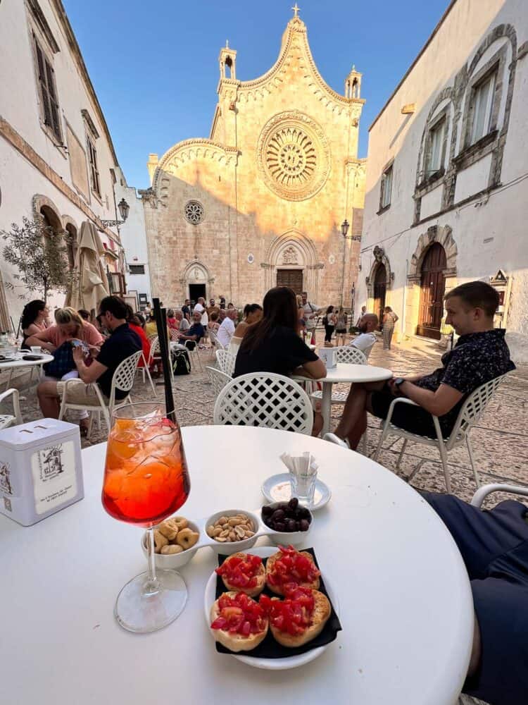 Aperol Spritz and aperitivo snacks at Gelateria Borgo Antico with a view of Ostuni Cathedral in Puglia, Italy